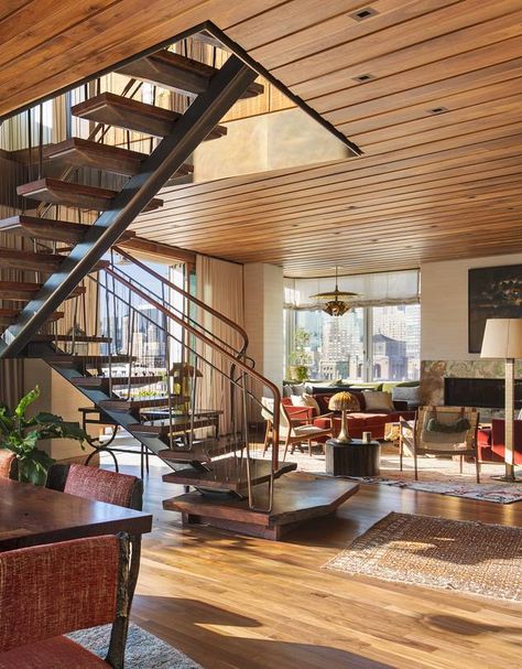 Airy Stair. Smack in the middle of this apartment’s living and dining spaces sits the stairway (pictured above), an element that could easily have blocked the view to the expansive terrace. The material of choice: slices of old-growth black walnut from Oregon, their organic live edges intact to distract from the room’s rigid geometry. The answer to making the steps “a feature but not an obstacle,” & risers between the heavy treads and using 1/8-inch bronze cable instead of traditional balusters. Stairs In Middle Of Living Room, Stairs Between Living And Dining, Stairs In The Middle Of The Room, Stairs In The Middle Of The House, Living Room With Stairs, Room With Stairs, Stairway Pictures, Staircase Slide, Cabin Stairs