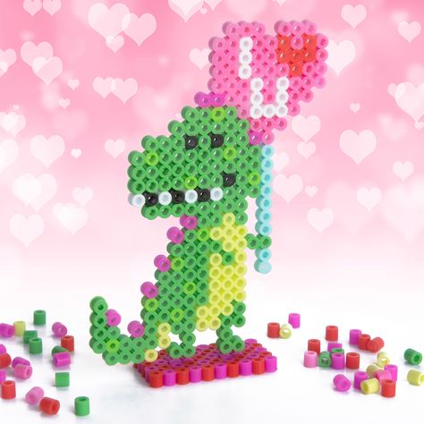 This cute little T-Rex is ready to spread love on Valentine’s Day! This fun and easy fused bead project will look great on a shelf, windowsill, or table. Peeler Bead Valentines, Perler Valentine Patterns, Perler Bead Valentine Patterns, Valentine’s Day Perler Beads, Perler Pins, Pixelated Art, Perler Designs, Easy Perler Bead Patterns, Lost Lands