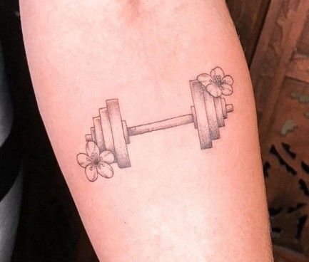 Floral Barbell Tattoo, Minimalist Barbell Tattoo, Dumbbell Tattoo Design For Women, Barbell Tattoo Weightlifting, Fitness Tattoos For Women, Sport Tattoo Ideas Women, Weightlifter Tattoo, Weightlifting Tattoos For Women, Dumbbell Tattoo Design