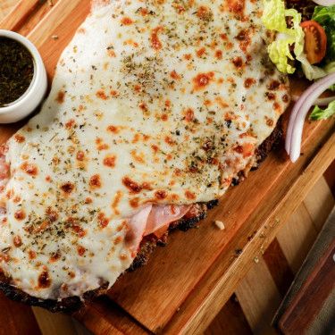 Milanesa Napolitana Al Plato from Food Network Milanesa Recipe, Breaded Steak, Recipes Restaurant, Sliced Ham, Shredded Mozzarella, Side Salad, Roasting Pan, Roasted Tomatoes, Steak Recipes