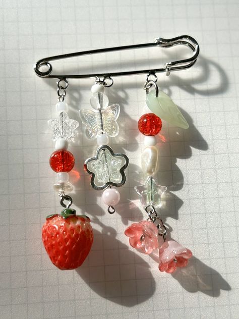 cute y2k inspired keychain pin with strawberries and stars! created uniquely for you and designed to be used in many places; on tote bags, bags, backpacks, lunchboxes, jackets etc. details: - large 2 inch pin with secure metal hook - charm and bead extension lengths vary from 2/2.5 inches - strawberry charm and glass flower and leaf beads - sparkles in sun, from iridescent beads - attached together by metal jump rings, some of which are recycled handmade with care, partially made with recycled metals and beads Cute Keychain Ideas, Things To Make With Beads, Extension Lengths, Keychain Y2k, Recycled Accessories, Bead Extensions, Aesthetic Pin, Strawberry Charm, Flower Keychain