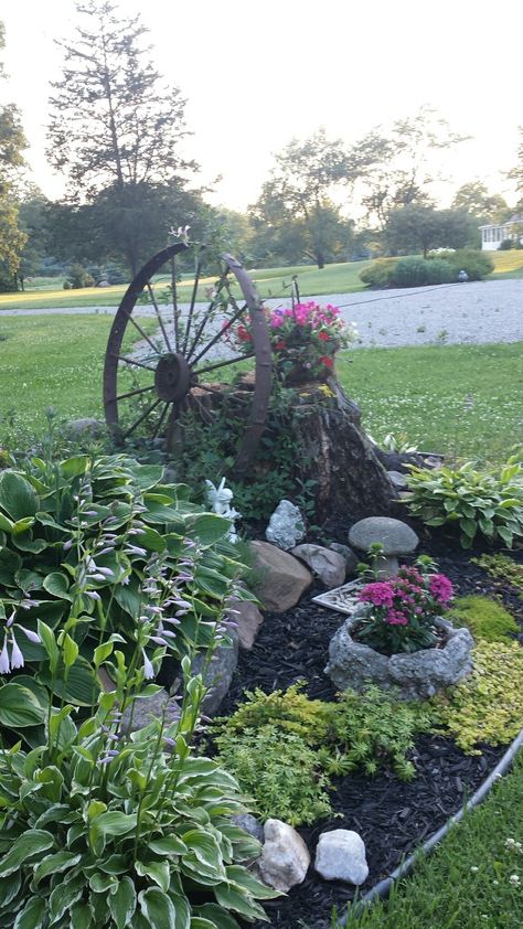 Large Stump Ideas Backyards, Landscape Around Tree Stump, Stump Landscaping Ideas, Stump Ideas Landscaping, Wagon Wheel Flower Bed Ideas, Landscaping Around Exposed Tree Roots, Tree Stump Flower Bed, Decorating Tree Stumps In Yard, Garden Ideas With Tree Stumps