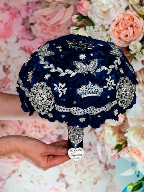 Behold the exquisite Quinceañera brooch bouquet in Navy Blue with silver colors! This quince bouquet shines with luxury and splendor, made with carefully chosen brooches of different shapes and sizes, crafted by hand.A handle wrapped in navy satin ribbon with attached heart that adds a personalized touch. This brooch bouquet is not only a beautiful accessory but also a cherished keepsake that captures the essence of your Quinceañera party. Bouquet size: 9 inches L x 13 inches HHand-made.Can be p Quinceanera Memory Ideas, Navy Blue Quinceanera Ideas Decor, Royal Blue And Silver Quinceanera Theme, Midnight Blue Quinceanera Theme, Dark Blue Quinceanera Theme, Navy Blue Quinceanera Ideas, Under The Stars Quinceanera Theme, Royal Blue Quinceanera Theme, Blue Quinceanera Ideas