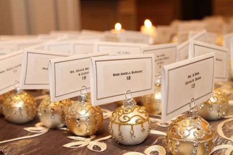 25 Awesome Christmas Wedding Ideas - Want to make your wedding a festive affair for the holidays? Here are a few holly jolly Christmas wedding ideas worth considering. table names escort seating ornaments gold {A Personal Touch} Ornament Table Numbers, Wedding Favors For Guests Christmas, Ornament Place Settings, Holiday Wedding Seating Chart, Ornament Place Card Holder, Christmas Ornament Table Number, Christmas Table Plan Wedding, Christmas Wedding Activities, Wedding Christmas Ornament Favor