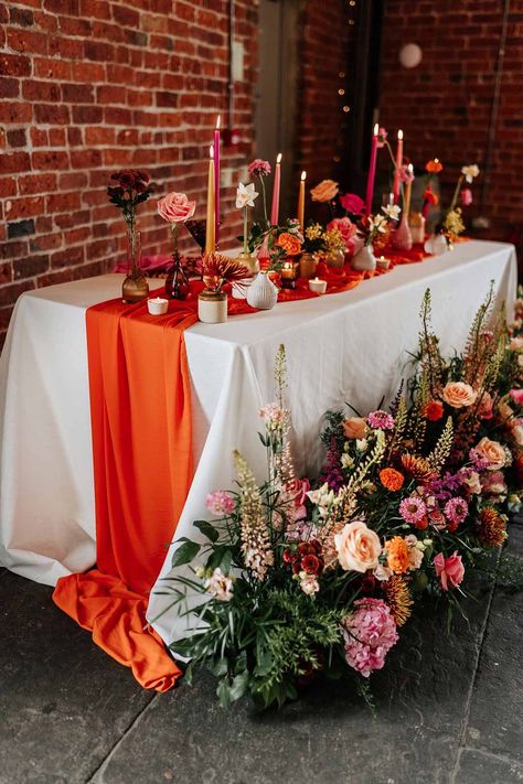 Retro wedding tablescape with pink tapered candles, orange table runner, mismatched single flower vases, colourful flower centrepieces and large colourful flower arrangements at Northern Monk Refectory Leeds | Stephanie Butt Photography Retro Editorial, Orange Table Runner, Orange Wedding Decorations, Flower Centrepieces, Raspberry Wedding, Orange Wedding Themes, Orange And Pink Wedding, Orange Wedding Flowers, Burnt Orange Weddings