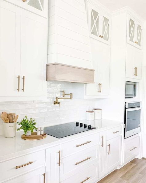 The white shiplap paneling along the range hood cover in this kitchen gives the space a rustic look while still matching the modern white cabinetry. For a splash of warm color, add gold hardware to the cabinetry and a few wooden prep tools to display along the white counters. White Kitchen Hood, White Herringbone Tile, Gray Tile Backsplash, Shiplap Paneling, White Subway Tile Backsplash, Modern Farmhouse Kitchen, Covet House, White Shiplap, All White Kitchen