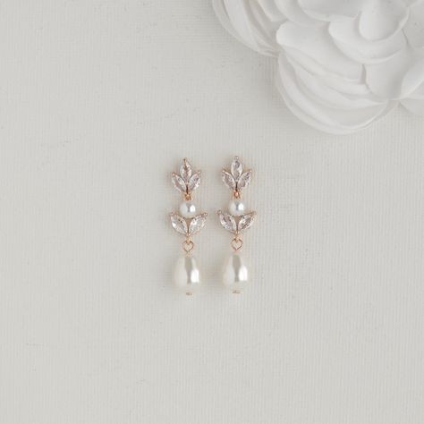 Gorgeous Pearl Earrings For Brides in Rose Gold These captivating Bridal pearl earrings in rose gold are the essence of understated elegance. The delicate floral design, adorned with sparkling cubic zirconia and pearls, adds a touch of intricacy to any outfit. Effortlessly Versatile:- Whether you are drawn to modern minimalism or timeless tradition, the rose gold finish beautifully complements both styles. The perfectly sized design ensures comfortable wear, adding a touch of sparkle without overwhelming your look. Crafted for Comfort and Longevity: Made with high-quality rose gold plating over stainless steel ear posts, these earrings prioritize both comfort and long-lasting wear. For added versatility, they are also available in classic yellow gold and sleek silver to perfectly match you Ethereal Earrings, Wedding Jewelry Ideas For Bride, Wedding Earrings Bride, Simple Wedding Earrings, Wedding Pearl Earrings, Bridal Pearl Earrings, Pearl Wedding Earrings, Pearl Bridal Earrings, Pearl Earrings Gold