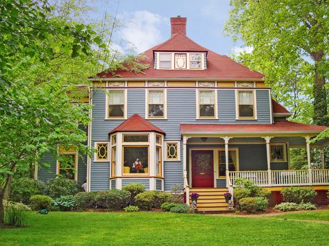 While bold, a red roof can be a good fit for gray, white, and taupe house colors. One way to be sure: Pick a variegated red shingle that folds in some of the siding color, like this oxblood roof, which incorporates hints of the blue-gray clapboards. Similar to shown: Supreme in Spanish Red, about $81 per square; Owens Corning House Exterior Red Roof, Blue House With Red Roof, House With Red Roof, Cottage Style Doors, Paint Combos, Red Roof House, Property Ideas, Shingle Colors, Roof House