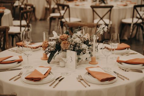 Burnt orange napkins and warm tone floral centerpieces accented with white plates and linens Wedding Table Decorations Burnt Orange, Burnt Orange Table Setting, Fall Wedding Table Settings, Wedding Dinner Table Setting, Orange Napkins, Napkins Wedding Table, Dried Greenery, Cocktail Table Decor, Neutral Florals