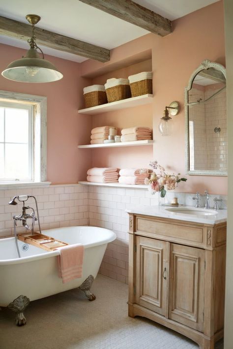 A country-style pink bathroom with wooden cabinetry and open shelving for a rustic feel. Pink Bathroom White Tiles, Bathroom Dusty Pink, Dusty Pink Bathroom Walls, Pink Cottage Bathroom, Pink And Sage Bathroom, Muted Pink Bathroom, Pink Master Bath, Baby Pink Bathroom, Pink Bathroom Ideas Decor