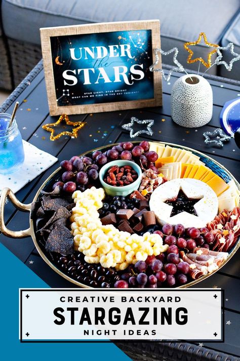 Moon & Stars themed charcuterie board, Under the Stars party sign, and decorative metallic pipe cleaner stars for a Backyard Stargazing Night Galaxy Theme Party Drinks, Space Foods Party, Two The Moon Party Favor Ideas, Space Theme Dinner Party, Galactic Party Food, Solar Party Food, Outer Space Fruit Platter, Full Moon Charcuterie Board, Solar Eclipse Cheese Board