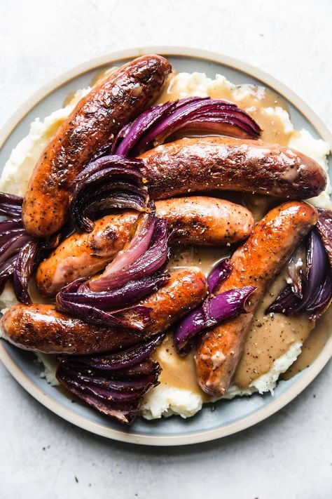 Nothing is quite as belly-warming as hearty British pub food, and our classic bangers and mash recipe is no exception. Bangers And Mash Recipe, Roasted Garlic Mashed Potatoes, The Modern Proper, Modern Proper, Mash Recipe, Bangers And Mash, Onion Gravy, Garlic Mashed Potatoes, Garlic Mashed