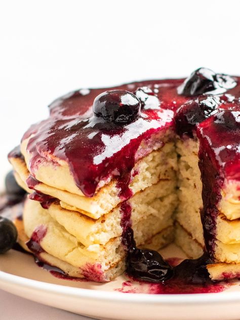 This is an overhead image of a stack of pancakes with blueberry glaze on top. The pancakes sit on a white plate on a white background. Blueberry Glaze, Blueberry Biscuits, Stack Of Pancakes, Yogurt Pancakes, Lemon Syrup, Pancake Stack, White Plate, Agave Nectar, White Plates