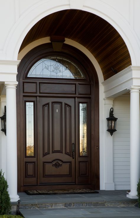 A beautiful wooden arch accentuates the curved window above the front entrance. Arch Window Above Front Door, Arch Top Front Door, Curved Door Design, Arch Wooden Design, Main Door Arch Design Entrance, Arch Main Door, Curved Ceiling, Curved Door, Oval Door