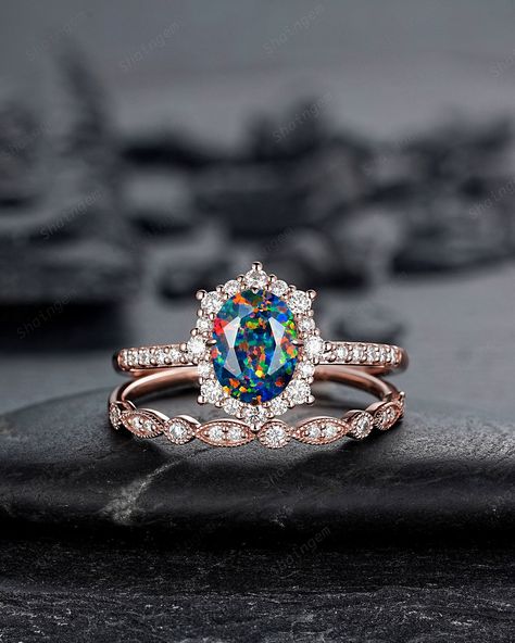 The opal Gemstone is a representative of justice and harmony, and is a protective stone in dangerous places. Opal has always been associated with love and passion, It is a seductive stone that intensifies emotional states and releases inhibitions. It can also act as an emotional stabilizer. Oval Shaped opal and halo moissanite engagement ring with black fire opal main stone and straight band ring set, pictured in rose gold, perfect as a modern wedding ring for a bride to be. Mixed Fire opal wedd Black Opal Wedding Ring, Opal Wedding Set, Unique Gemstone Engagement Rings, Black Opal Engagement Ring, Fire Opal Engagement Ring, Opal Engagement Rings, Opal Wedding Ring, Lab Black, Vintage Opal Engagement Ring