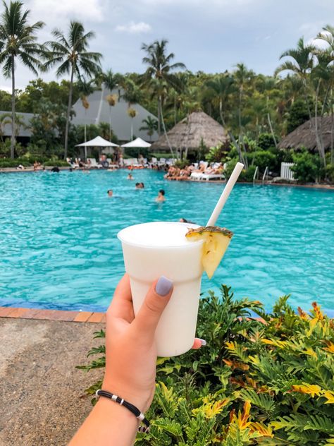 Hand extended in foreground with piña Colada in hand. Behind drink is a pool resort with swim up bar. Swim Up Bar Pool, Daydream Island, Hamilton Island Australia, Australia Party, Island Pool, Pool Resort, Travel Vibes, Hamilton Island, Swim Up Bar