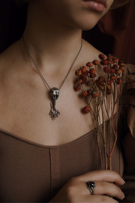 Heavy silver skull holding a branch full of berries. Wiccan aesthetic, Modern witch aesthetic, Witchcore, Whimsigothic aesthetic, Designer witchcore jewelry, Vintage wiccan jewelry, Nature inspired jewelry, Dark fashion aesthetic, Witchy fashion photography, Vintage fashion photography, Vintage twig pendant, Vintage branch pendant, Wild nature pendant, Vintage style pendant, Designer bird scull pendant, Designer raven scull pendant, Dark forest aesthetic, Fairycore aesthetic, Jewelry editorial Dark Silver Jewelry Aesthetic, Forest Witch Jewelry, Dark Jewelry Photography, Witch Jewelry Aesthetic, Witchcore Jewelry, Dark Fashion Aesthetic, Modern Witch Aesthetic, Wiccan Aesthetic, Dark Silver Jewelry