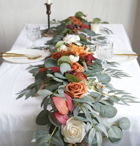 The realistic and natural flowers perfectly blend with eucalyptus leaves and willow, helping to create a romantic ambiance. Eucalyptus Garland Centerpiece, Orange Flower Garland, Eucalyptus Runner, Sweetheart Table Centerpiece, Garland Centerpiece, Table Garland, Flowers For Wedding, Banquet Table, Wedding Arch Flowers