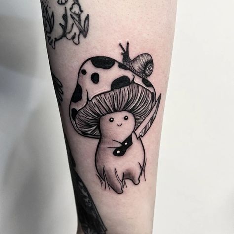 Black and grey tattoo of a mushroom man holding a little knife with both of his hands. There is a small snail on the top of the mushroom man's head on one side Evil Mushroom Tattoo, Mushroom Tattoo Ideas For Men, Goofy Mushroom Tattoo, Mushroom Knife Tattoo, Cute Animals Holding Knife Tattoo, Mushroom With Knife Tattoo, Lady With Mushroom Head Tattoo, Mushroom Holding A Knife Drawing, Mushroom Animal Tattoo