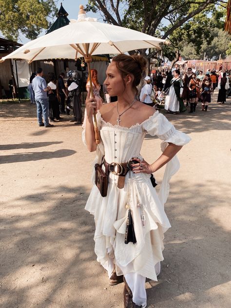 White woman with blonde hair tied into a bun, wearing a white gown with white corset. A leather belt carrying a book and chatelaine. She’s holding a white parasols. Ren Fest Costumes Women Shoes, Medival Outfits Woman Pants, White Ren Faire Outfit, Rem Faire Costume, Rennassaince Faire Outfits, Ren Faire Wench, Rennaisance Faire Outfit Fairy, Renn Faire Costume Women, Renecansse Fair Outfits