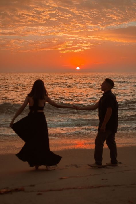 young couple dancing with the sunset to la vie en rose. girl is wearing black dress and boy is in khakis and a dark button up. The sun is setting behind them, spreading a bright orange and pink hue across the sky and into a set of clouds at the very top of the photo.the photo is taken at a beach in La Jolla San Diego California. Couples On Beach Sunset, Sun Set Couple Photos, Sunset Couple Photography Beach Photo Ideas, Couple Beach Sunset, Goa Couple, Golden Hour Beach Engagement Photos, Sunset Photoshoot Ideas Golden Hour, Sunrise Engagement Pictures Beaches, Proposal On Beach