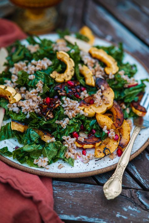 A Kale Pomegranate Salad with roasted delicata squash, farro, pumpkin seed brittle, and apples. Tossed in a dijon vinaigrette. The perfect vegan holiday salad for Thanksgiving or Christmas. Pumpkin Brittle, Salad For Thanksgiving, Pumpkin Seed Brittle, Roasted Delicata Squash, Holiday Salad, Holiday Salads, Massaged Kale, Dijon Vinaigrette, Pomegranate Salad