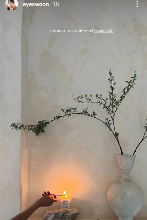 Photo of a big, light stone vase with a couple of green branches in front of a light, limewashed wall. A person lights a candle in the bottom part of the photo. Minimal Massage Room, Eyeswoon Bathroom, Bathroom Limewash, Limewash Bathroom, Bathroom Greenery, Spa Vibes, Massage Room Design, Massage Therapy Rooms, Spa Studio