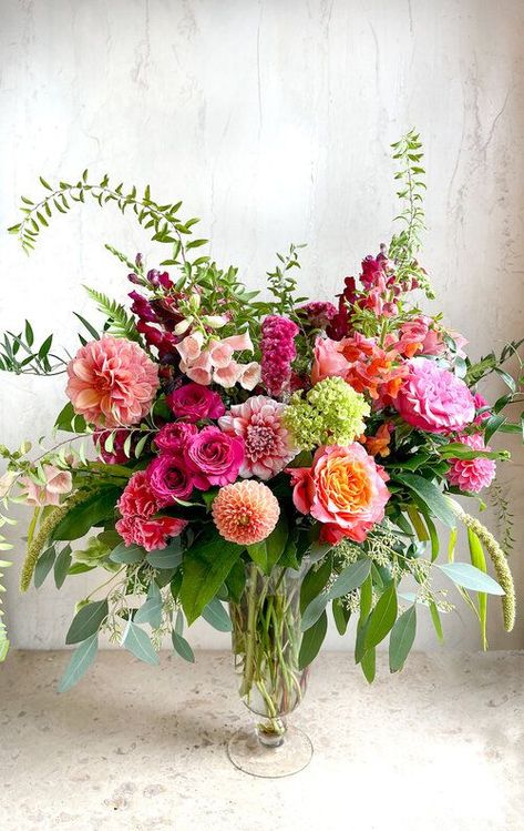 Eclat de Couleurs- Fall floral arrangement. This lovely arrangement stands tall with locally grown dahlias and bursts of bright colors. Orange and different shades of pink with whimsical greens in a tall glass vase. Pink Flowers Arrangements Vase, Flowers In Vase Arrangement, Vivid Flower Arrangements, Tall Vase Bouquet, Pink Orange Yellow Floral Arrangement, Spring Table Flowers, Dahlia Vase Arrangement, Dahlia Flower Arrangements Centerpieces, Dahlia Flower Wedding Centerpieces