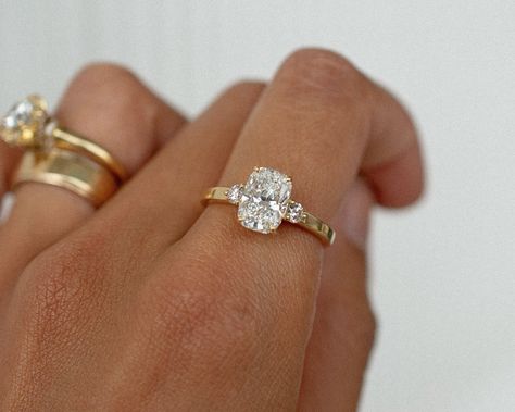 A gorgeous recent custom piece, with a 2.06 elongated cushion cut dimond, 2 round diamond accent stones, set into a low band flat band for a modern feel ✨ Details: - 2.06ct elongated cushion diamond - 2x round diamonds - 18k yellow gold - 2mm wide shank #elongatedcushion #customengagementring #engagementringideas #engagementringdesign #threestoneengagementring #nz #aus Engagement Rings Flat Setting, Cushion Cut Engagement Ring With Thick Band, Elongated Cushion Cut 3 Stone Ring, Cushion Ring Stack, Cushion Engagement Ring Set, Cushion Cut Elongated Engagement Ring, Small Elongated Cushion Engagement Ring, Rounded Cushion Engagement Ring, Cushion Elongated Engagement Ring