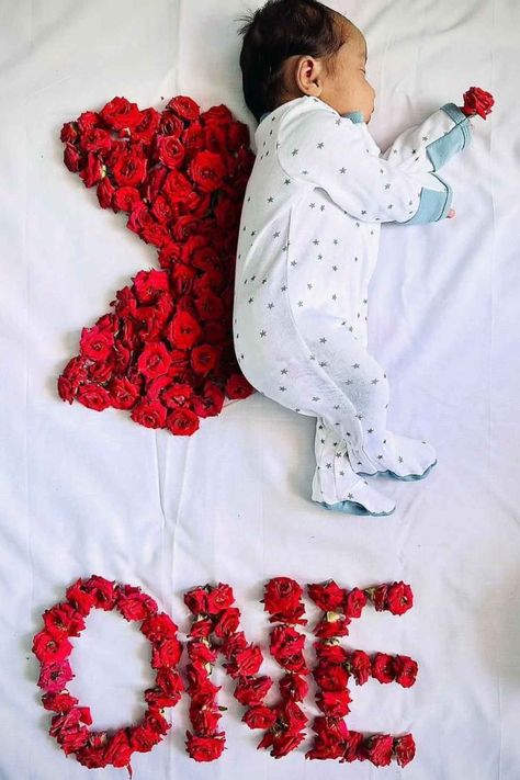 A baby laying on a bed with red roses arranged in the shape of a wing. 1 Months Baby Photoshoot Ideas, Months Photos Baby Ideas, Monthly Baby Photos Girly, Newborn Monthly Pictures Photo Ideas, Baby 100 Days Photo Ideas, Photo Shoot Ideas For Baby, February Baby Photoshoot, Newborn Baby Shoot Ideas, Baby One Month Photo Ideas