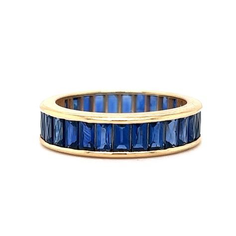 French Cut Blue Sapphire Eternity Band in 18k Yellow Gold A glamourous, modern stacking band in bold blue sapphires! This French Cut Sapphire eternity band is finished in 18 karat yellow gold. This sleek stacking ring features 5.51 total carats of French cut blue sapphires set in a channel around the entire band. Streamlined with scintillating color. This gemstone ring is a jewelry designer's dream.  A colorful band to check off your search for Something Blue. Primary Stone: Natural Blue Sapphire Shape and Measurements: 3.70 mm x 2.70 mm x 1.80 mm = .19 ct (29) Stone Weight: 5.51 ct General Characteristics: Height Above Finger: 2.15 mm Measurements: 5.12 mm Total Gram Weight: 4.1 g Ring Size: 6.0 Resizable: No Era: Modern 1970-Present -- ALL PIECES ARE SUBJECT TO PRIOR SALE DUE TO HAVING A Blue Sapphire Eternity Band, Pave Diamond Wedding Bands, Sapphire Eternity Band, Sapphire And Diamond Band, Contour Wedding Band, Sapphire Wedding Band, Sapphire Band, French Cut, Sapphire Wedding