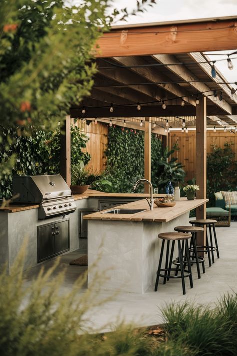 Outdoor kitchen under a wooden pergola with grill, sink, bar stools, and potted plants. Outdoor Bbq Seating Area, Outdoor Summer Kitchens, Kitchen To Patio Transition, Bbq Design Ideas, Small Outdoor Kitchen And Bar, Outdoor Bbq Terrace, Outdoor Kitchen On Side Of House, Outside Bbq Ideas, Bbq Deck