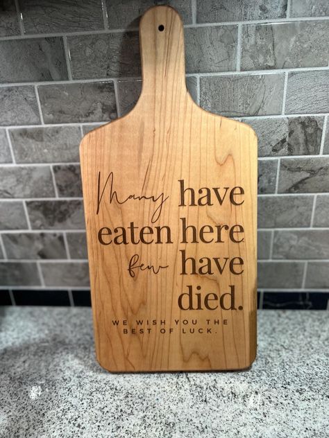 Few Have Died Serving Board | Breadboard | Cheeseboard | Kitchen Decor | Funny Kitchen Decor | Charcuterie Board | Serving Board This listing is for a handmade wooden breadboard with the phrase "Many have eaten here, few have died" engraved on it. This serving board is food safe, and comes with board butter to keep it in tip top shape.  This charcuterie board makes a great gift for someone that is notoriously not an amazing chef or is a fun addition to your own kitchen. These boards are cut by h Funny Wood Burning Ideas, Wood Burning Charcuterie Board Diy, Charcuterie Sayings, Charcuterie Board Engraving Ideas, Wood Burning Ideas Gifts, Lazer Engraver Ideas, Laser Engraving Ideas Projects, Charcuterie Board Designs, Engraver Ideas