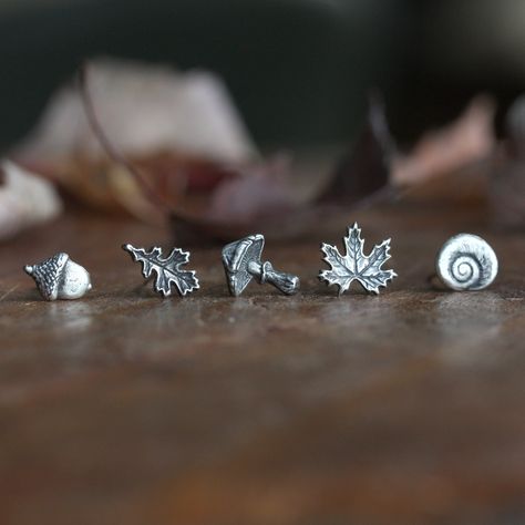 One single Autumn earring stud ~ sculpted in fine silver with sterling silver posts and backings. Dainty, elegant and perfect for every day. Choose from  Acorn, Oak Leaf, Mushroom, Maple Leaf or Shell. This listing is for ONE (1) single stud earring. These earrings feature tiny hand sculpted, autumnal themed nature treasures that were molded in fine silver (.999 / 99.9% pure silver) from an original design and then hand sculpted with further details before firing. The posts are sterling silver (.925) with sterling silver clutch backings. They are available in two different sizes that you can select at checkout: ✥ Small ~  The Acorn earring measures approximately 6mm wide x 8mm high;  The Oak Leaf earring measures approximately 5mm wide x 10mm high;  The Mushroom earring measures approximat Mushroom Earring, Small Stud Earrings, Nature Stud Earrings, Autumn Earrings, Mushroom Earrings, Autumn Jewelry, Silver Nature-inspired Metal Earrings, Acorn Earrings, Maple Leaf Jewelry