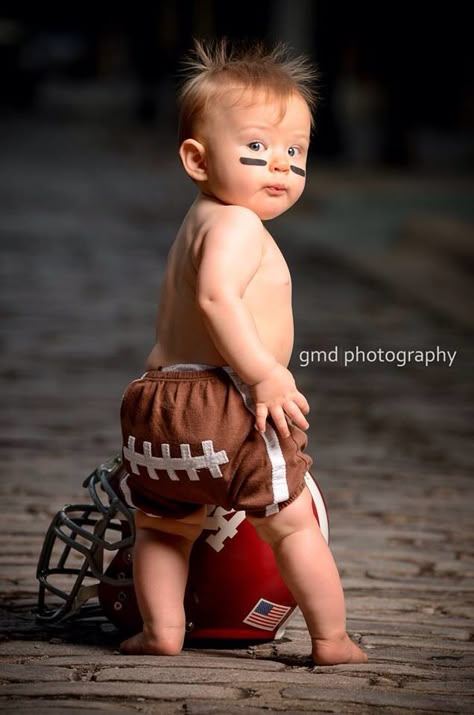 Infant with football shorts and father's helmet. First Year Down Football Photoshoot, Football Birthday Photoshoot, First Down Photo Shoot, 1st Year Down Football Birthday Photoshoot, One Year Football Photoshoot, First Year Down Photoshoot, Football First Birthday Photoshoot, One Year Old Football Photoshoot, Football First Birthday Pictures