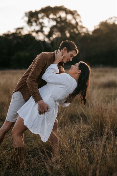 Cute white dress for photos ] Golden hour photos] Gorgeous field photos] Cute poses] photos in the grass Grass Couple Photoshoot, Field Engagement Photos, Field Photos, Engagement Photoshoot Ideas, Golden Hour Photos, Cute White Dress, Pic Poses, Outdoor Couple, Couple Picture