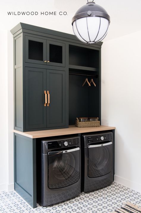 Step into simple sophistication with this dark green laundry room featuring Benjamin Moore Dark Pewter cabinets. The dark green color scheme adds a sense of elegance, while the modern laundry room design elements create a stylish and functional space. Ideal for a laundry room renovation for those seeking a combination of style and practicality. Visit Wildwood Home Co at wildwoodhomecompany.com to see our full service residential architect and interior design studio and curated shop of homewares. Powder Laundry Room, Shared Laundry And Bathroom, Small Laundry Sink Ideas, Laundry Room With Dark Cabinets, Ultimate Laundry Room, Champagne Washer And Dryer Laundry Room, Benjamin Moore Dark Pewter, Laundry Room Design Cabinets, Dark Green Laundry Room