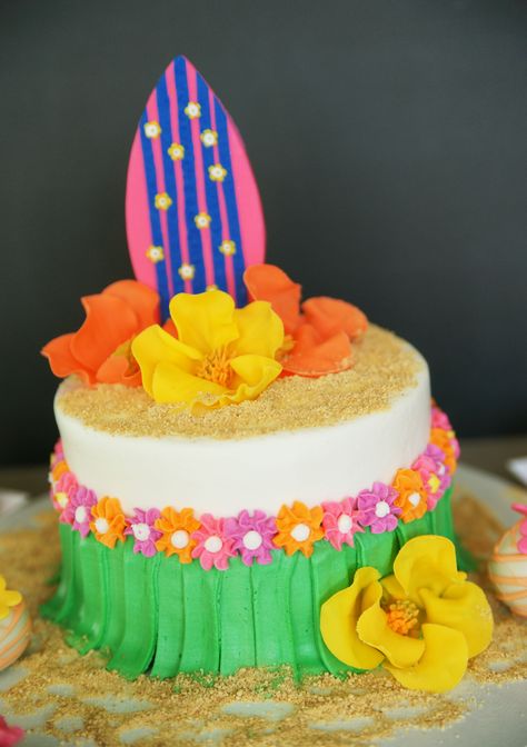 A one-tiered Hawaiian Themed cake with gum paste surf board, hibiscus and buttercream grass skirt Hawaiian Party Cake Ideas, Hawaiian Cake Design, Hawaiian Cake Ideas, Hawaii Birthday Cake, Hawaiian Themed Cake, Hawaiian Party Cake, Luau Birthday Cake, Hawaiian Cakes, Luau Party Cakes