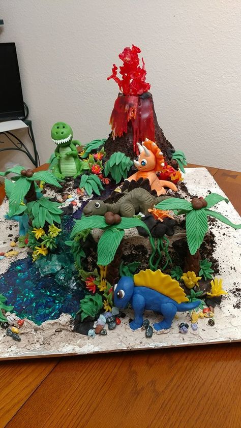 First BD cake for Great Grandson. Cake is Chocolate with cookie and cream filling. Frosted in vanilla whipped frosting sprinkled with oreo cookies for "cooled lava" Volcano is RKT covered in modeling chocolate. The Lava is Isomalt with light. All Decorations are Modeling clay. The river/pond is isomalt. The Dinos are hand sculpted in modeling chocolate. Gingerbread Volcano, Salt Dough Volcano, Volcano Clay Model, Volcano Clay, Diy Volcano Cake, Volcano Sculpture, Ceramic Volcano, Bd Cake, Clay Models