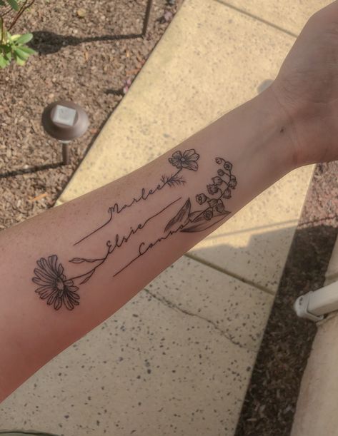 This tattoo was created for my 3 kiddos! Each child’s name goes with each of their birth month flowers. Cosmos for October, daisy for April, and lily of the valley for May. Tattoo Ideas With Names, Tato Nama, Name Flower Tattoo, Cosmos Tattoo, Daisy Tattoo Designs, Kid Name Tattoo, Flower Tattoo Ideas, Tattoos With Kids Names, Omerta Tattoo