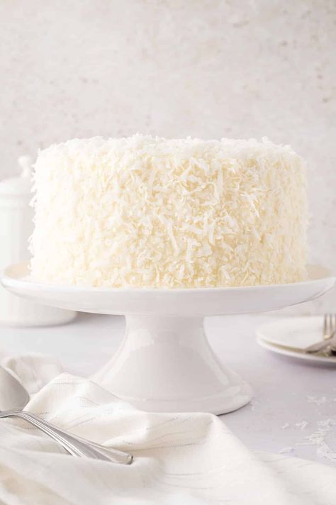 An 8-inch coconut cake on a cake stand. Ina Garten Coconut Cake, Taco Bell Recipes, Coconut Buttercream, Cake Rolls, Coconut Cake Recipe, Ina Garten Recipes, Make Cream Cheese, Coconut Frosting, Coconut Cake