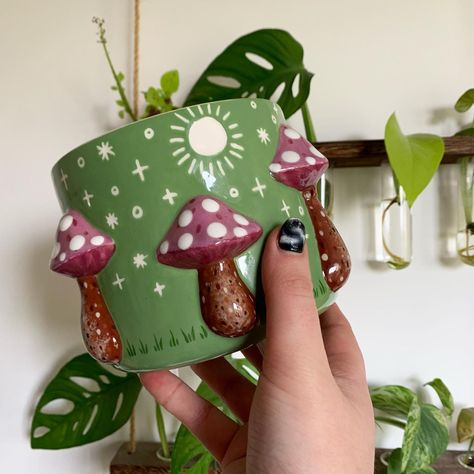 I am SO excited to share the second of three limited hand painted toadstool planters with you all from my latest kiln firing! This pretty green themed version is going to be heading over to @bloomandwhimsy in May where I’m going to be their guest artist for the month!!! Sooo unbelievably excited and grateful for this opportunity ✨🥰🌿 … who’s going to snap it up first and take it home? 🥰✨🌷 Can’t wait to share the final version of this plant pot in a little while…. What colours would you like ... Pot Plant Painting Ideas, Plant Mug, Witchy Things, Purple Design, Creative Things, Ceramics Ideas Pottery, Illustrators On Instagram, Kiln Firing, Pretty Green