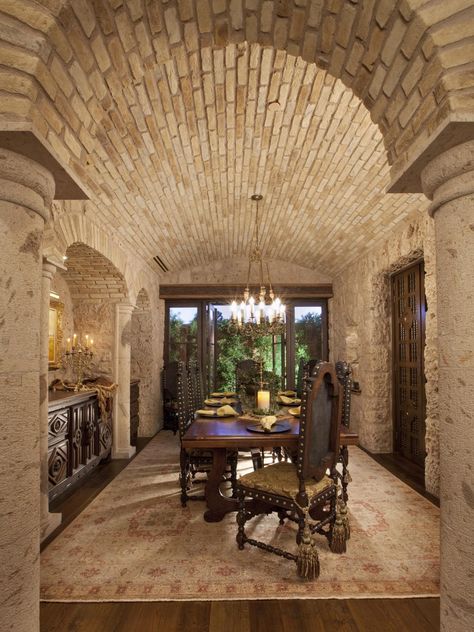 With its brick barrel ceiling and rough stone walls, this dining room could double as a wine cellar. Heavy, hand-carved dining chairs surround a wood dining table under the glow of a filigreed chandelier. Tuscan Dining Room, Tuscan Dining Rooms, Tuscan Style Decor, Style Toscan, Italian Style Home, Tuscan Homes, Stone Walls Interior, Tuscan Style Homes, Tuscan Home