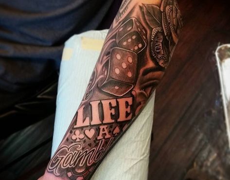 Do you believe that "life is a gamble"? Thinking of getting a tattoo as a reminder? Here are popular 'life's a gamble' tattoo ideas that you will love. @andywesttattooartist via Instagram 'Life is a gamble' tattoo represents risk-taking, stakes and uncertainty in life. Do you believe that living life's a… Life’s A Game Tattoo, Life’s A Risk Tattoo, Life S A Gamble Tattoo, Life A Gamble Tattoo Design, Game Of Life Tattoo, Life’s A Gamble Tattoo Arm, Lifes A Gamble Tattoo Forearm, Life Is A Gamble Tattoo Ideas, Life’s A Gamble Tattoo Design