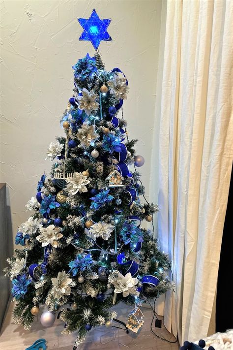 I have adopted a Christmas custom and applied it to Hanukkah. Our tree is adorned with Hanukkah-related decorations, white lights, and blue ribbons. I even added in silver and blue poinsettias. After all, it is the festive time of year. Hanukkah Tree Ideas, Hanukkah Tree Decorations, Hanukkah Tree, Christmas Custom, White Lights, How To Decorate, Family Holiday, Blue Ribbon, Custom Christmas