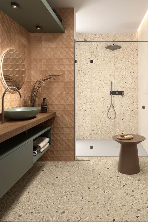 Rich in character and contrast, Arkistyle is a collection by Marca Corona that reinterprets Terrazzo tiles. Its Shade Warm variant flows beautifully both on the bathroom floor and the shower wall. Above the sink, Terracreta Forma Chamotte and its smooth embossment adorn the space with a soft caramel shade and complement the Multiforme Dune Tufo porcelain stoneware reflected on the mirror. Terrazo Tiles Bathroom, Terrazzo Tiles Bathroom, Bathroom Tiles Combination, Bathroom Inspiration Modern, Unglazed Porcelain, Beige Tile, Terrazzo Tiles, Italian Tiles, Tile Stores