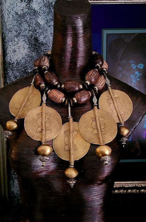 This stunning bespoke African tribal - ethnic oversized beaded chest piece is from my private vault and it is now available for purchase! Five oversized African lost wax brass Baule sun disks are featured in this piece. Each of these 3.5" jumbo size brass beads are currently retailing for $100.00 each!! A huge brass bicone is suspended from the end of each disk along with a brass rhinestone rondelle, various metal beads and a black seed bead. The necklace adjusts from 16-20" and closes with gold tone hardware, a fancy xl lobster claw clasp and a 4" extender chain. The necklace is comprised of huge wood beads, wood rondelles, brass spacers, African lost wax brass beads and ornate gold tone round beads. A lightweight and comfortable piece from the Atelier of Kat Kouture! Worldbuilding Clothes, Rocker Chic Accessories, Trill Art, African Inspired Decor, African Royalty, Unique Pendant Necklace, African Necklace, African Textiles, Brass Beads