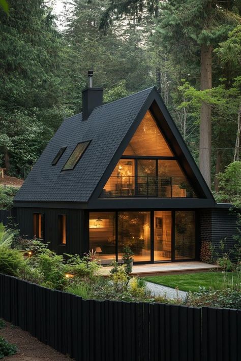 Modern tiny a frame cabin with black roof and siding full wall glass window multi pitched roof black wooden fence in front lush forest in the. Unlock the charm and coziness of A-frame cabins and learn why they might just be the coolest little homes on the block. Tiny Forest House, Modern Forest Cabin, Black A Frame Cabin, Cabin Modern Interior, Black Wooden Fence, Black Wooden House, Modern A Frame House, Tiny A Frame, Tiny Barndominium