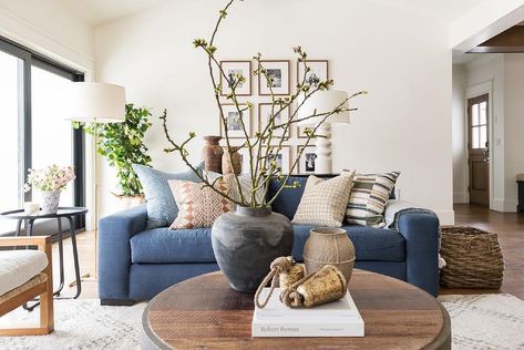 Denim blue sofa with a round black salvaged end table accented with decorative pieces atop a cream Morrocan rug in a cottage living room. Denim Blue Sofa, Northridge Remodel, Blue Sofas Living Room, Blue Couch Living Room, Wall Art Inspiration, Interior Design Aesthetic, Blue Couch, Blue Couches, Beige Living Rooms