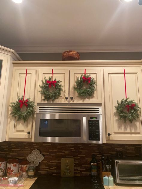 Black Kitchen Cabinets Christmas Decor, Christmas Over Cabinet Decor, Above The Cabinets Christmas Decor, Bows For Cabinet Doors, Christmas Decor Small Kitchen, Christmas Present Cabinets, Wreaths Kitchen Cabinets, Christmas Decorations For Cabinets, Christmas Decor Ideas For Kitchen Cabinets